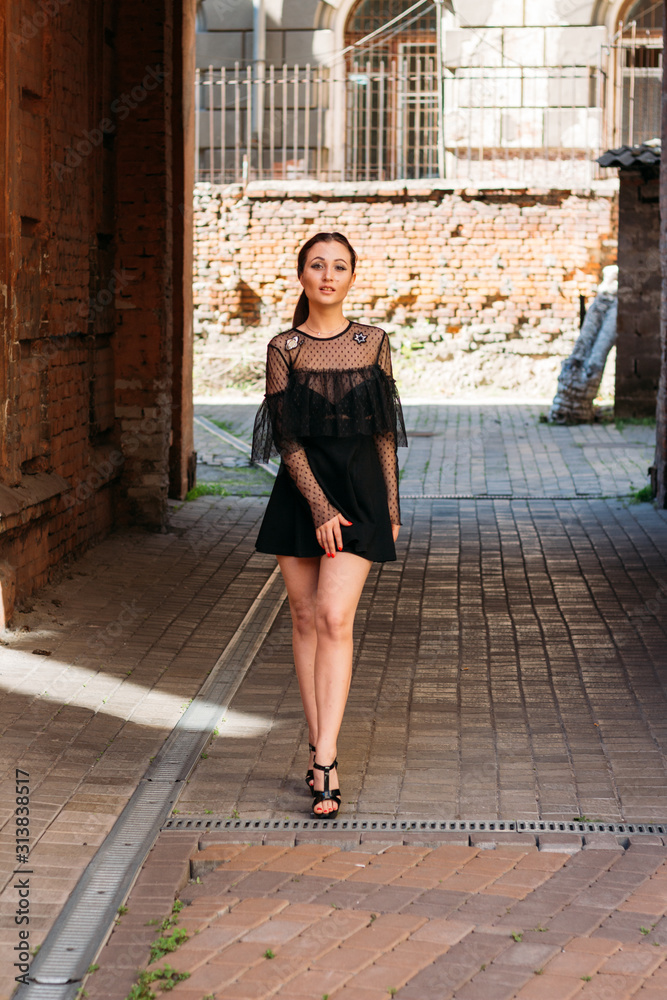 the girl is posing smiles. Emotional portrait of Fashion stylish portrait of pretty young woman. city portrait. brunette in a black dress. expectation. dreams