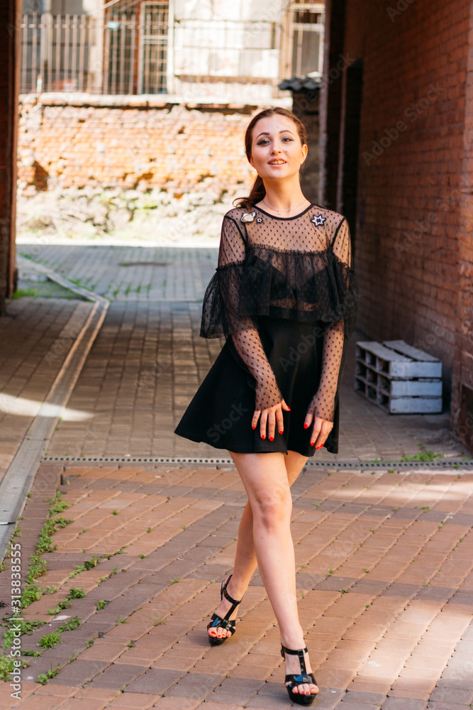 the girl is posing smiles. Emotional portrait of Fashion stylish portrait of pretty young woman. city portrait. brunette in a black dress. expectation. dreams the girl is posing smiles. Emotional portrait of Fashion stylish portrait of pretty young woman. city portrait. brunette in a black dress. expectation. dreams