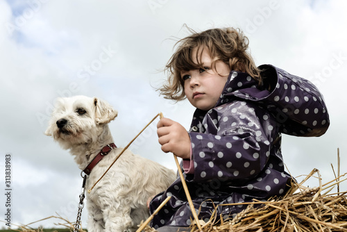 cute young girl on a haystack with her dog