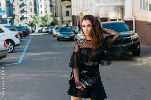 portrait of a girl, brunette, in a black dress, in the arch, in the city. posing, walking. alone in the crowd, loneliness.sad