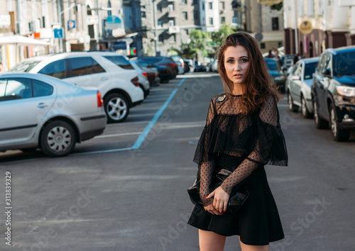 portrait of a girl, brunette, in a black dress, in the arch, in the city. posing, walking. alone in the crowd, loneliness.sad