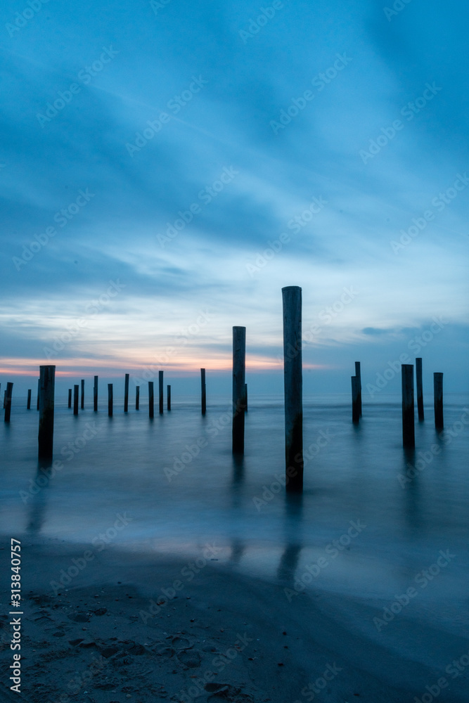 Poles at the sea during blue hour Poles at the sea during blue hour