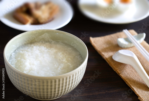 Boiled rice in gray bowl with food for eating which has chopstick with spoon all put  on dark wooden table