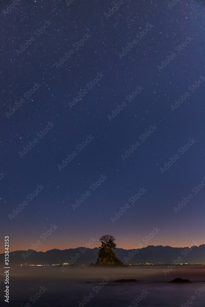 Fototapeta premium 夜明け前の雨晴海岸から女岩と立山連峰に昇る星空