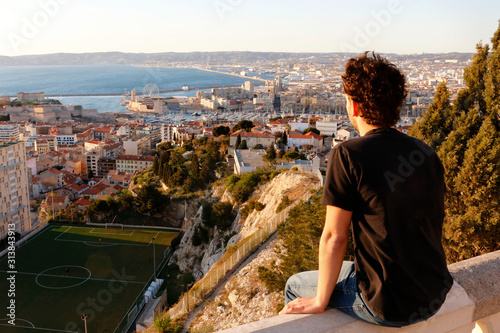 Male teenage model looking over Marseille in the sunset