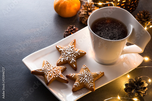 Christmas homemade gingerbread cookies on plate with cup of tea on table