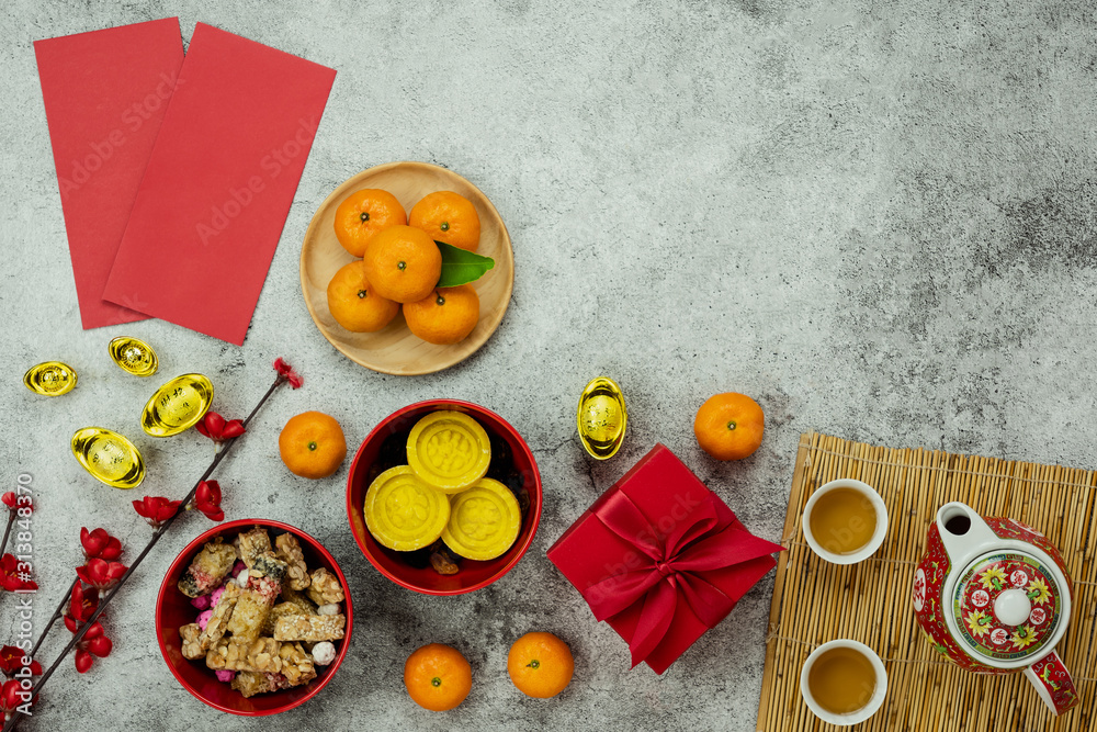 Chinese language mean rich or wealthy and happy.Top view of Lunar New Year & Chinese New Year vacation concept background.Fresh orange & cup of tea with pink cherry flower and food on grey cement.