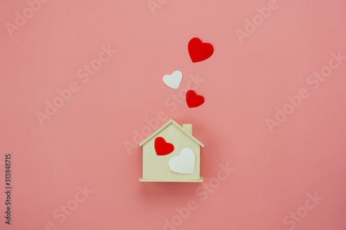 Table top view aerial image of decoration valentine's day background concept.Flat lay essential items colorful pastel love shape with wooden house on modern rustic pink paper.Mock up creative design.