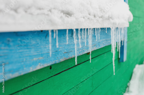 Icicles hang from the window of wooden house