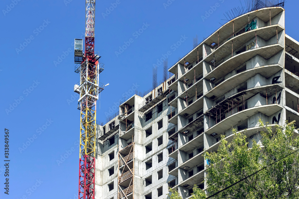 the construction crane and the building against the blue sky. the construction crane and the building against the blue sky.