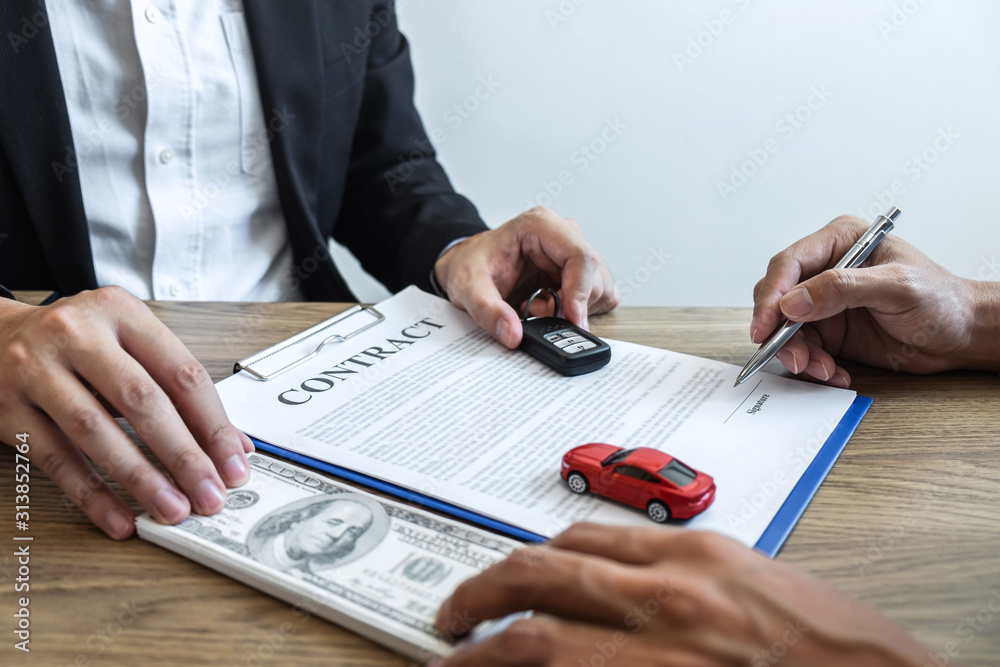 Car rental and Insurance concept, Young salesman receiving money and giving car's key to customer after sign agreement contract with approved good deal for rent or purchase Car rental and Insurance concept, Young salesman receiving money and giving car's key to customer after sign agreement contract with approved good deal for rent or purchase