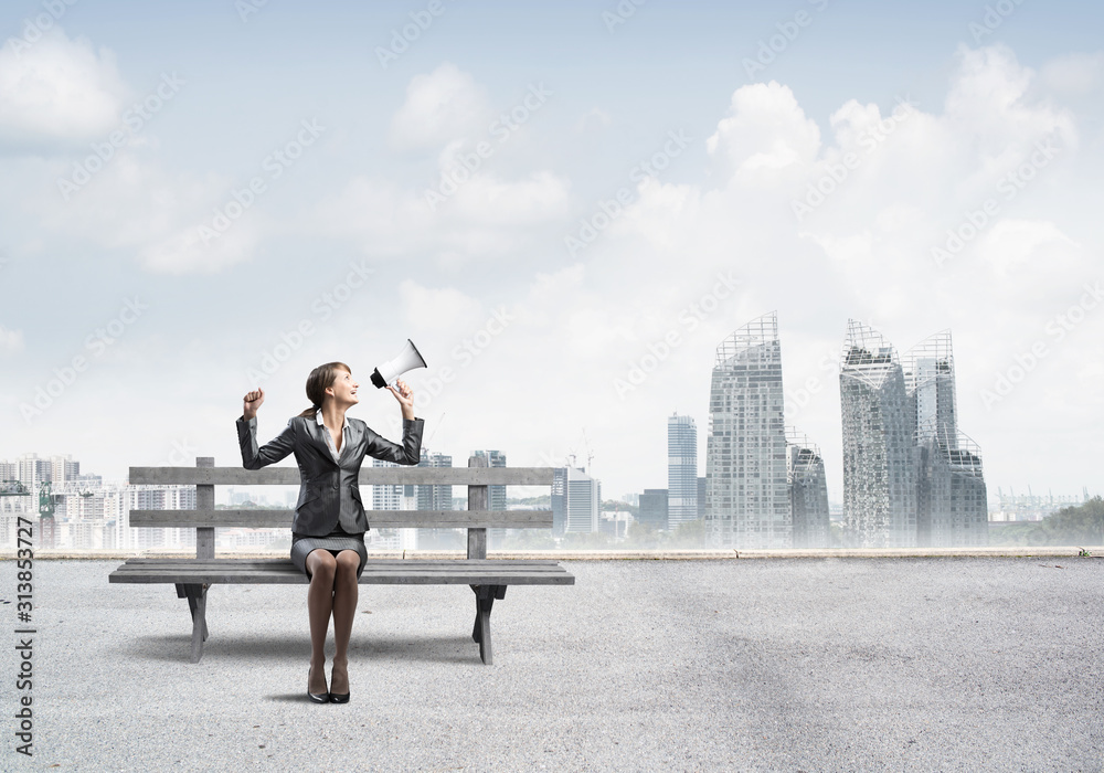 Business woman with megaphone sitting on wooden bench Business woman with megaphone sitting on wooden bench