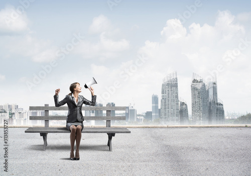 Business woman with megaphone sitting on wooden bench © adam121