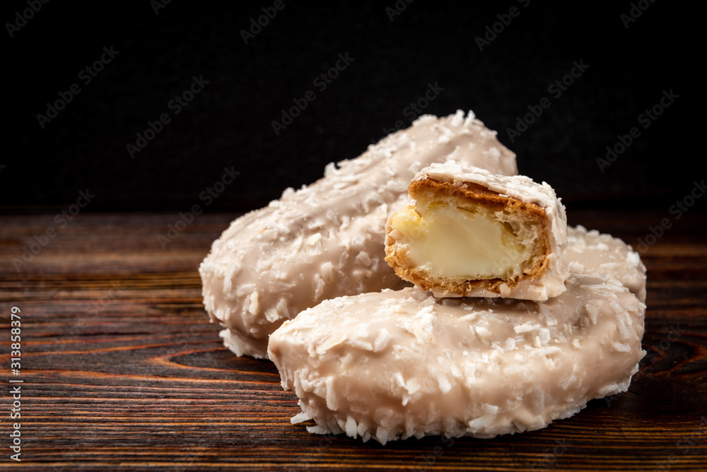 Coconut eclairs or custard cookies on dark wooden background. Coconut eclairs or custard cookies on dark wooden background.