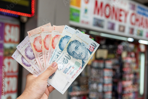 Hand holding Singapore dollar banknotes, currency exchange concept photo