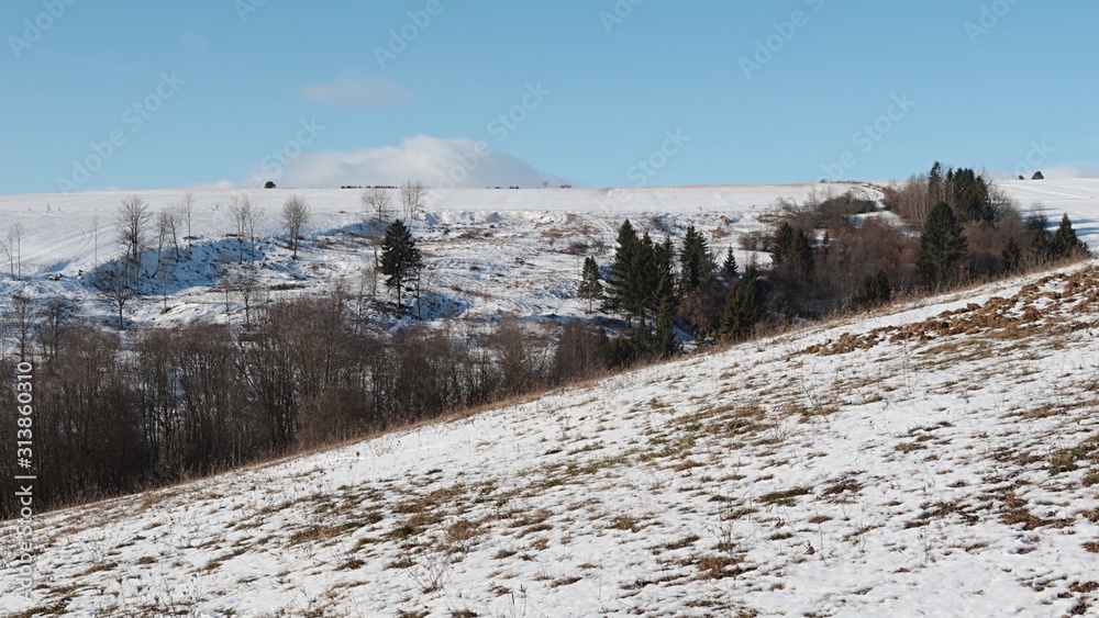 Winter half snow covered pastures and fields under Low Tatras mountains near village of Liptovsky Ondrej