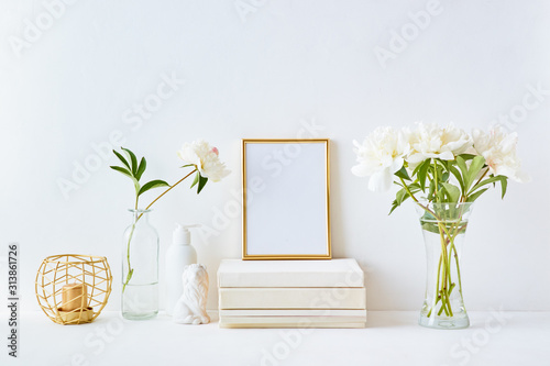 Fototapeta Naklejka Na Ścianę i Meble -  Home interior with decor elements. Gold frame, white peonies in a vase, interior decoration