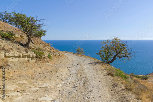 A dirt road running along a deserted mountainside on the seashore.