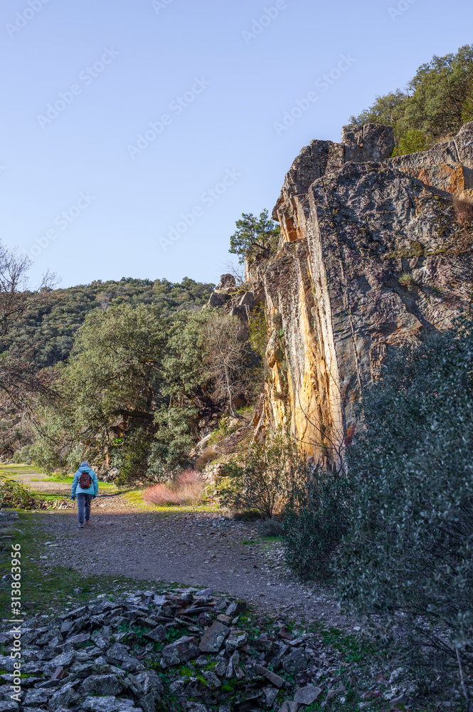 Hiker walking close quarzite formations, National Park of Cabaneros Hiker walking close quarzite formations, National Park of Cabaneros