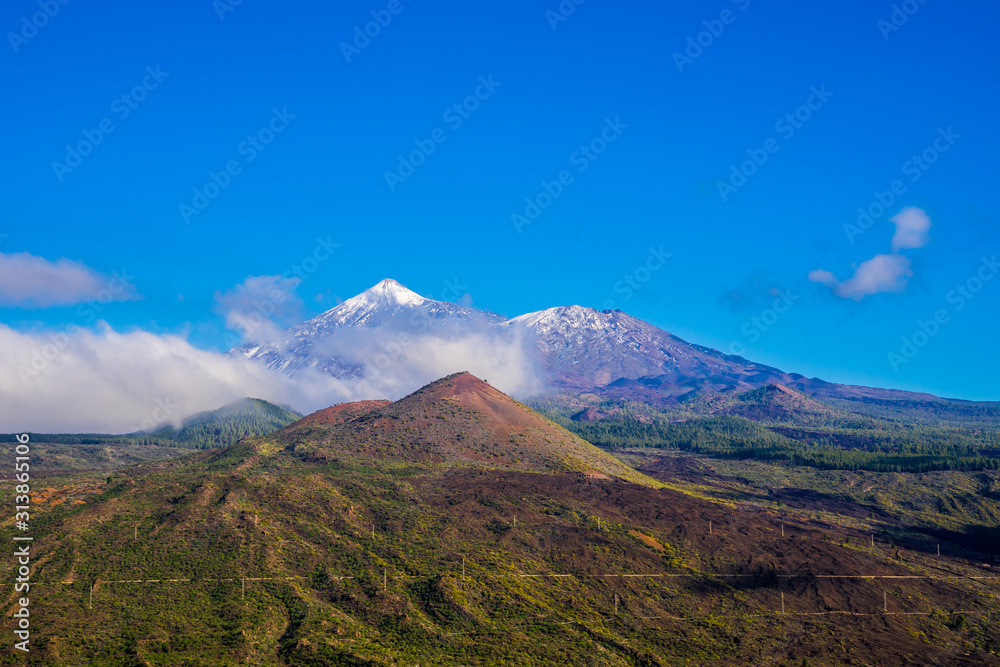 Spain, Tenerife, Aerial view above colorful forested mountains nature landscape of teide national park, peak of volcano teide covered by white snow