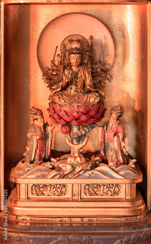 Golden wooden statue depicting the bodhisattva Jundei depicted sit down on a red lotus in the Tendai Buddhism Gokokuin temple in the Ueno district of Tokyo. photo