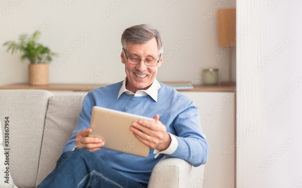 Happy Mature Man Using Tablet Sitting On Couch At Home Happy Mature Man Using Tablet Sitting On Couch At Home