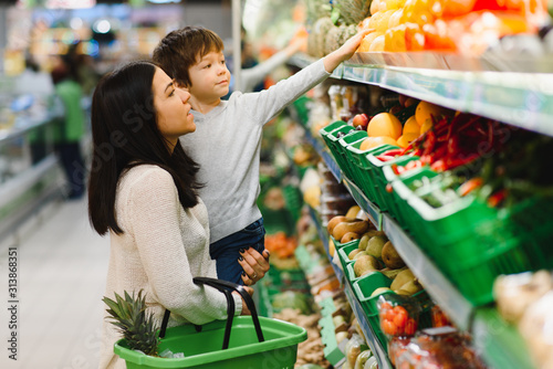 Foto Mother and child shopping at farmer's market for fruits and vegetables