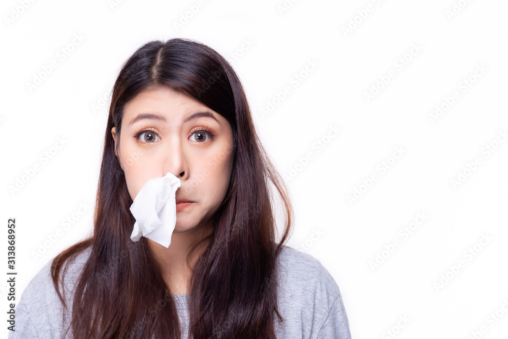Asian woman put tissue paper in her nose. She have a stuffed nose or runny nose. Pretty girl has a cold or be allergic to weather. It's winter time or rainy season, hay fever is playing up. copy space