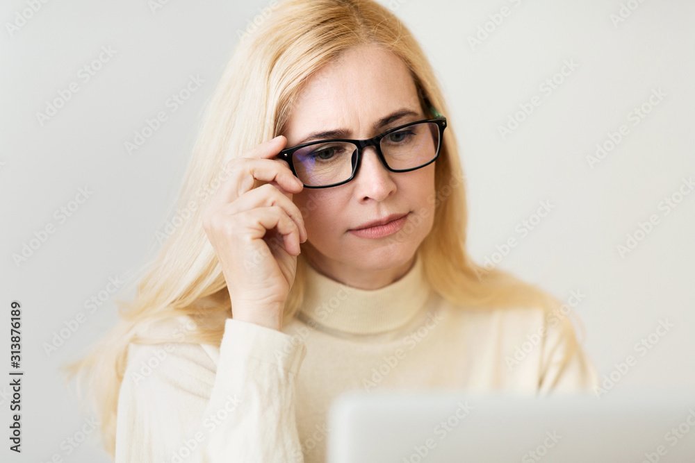 Eyesight problem. Woman looking through eyeglasses at laptop Eyesight problem. Woman looking through eyeglasses at laptop