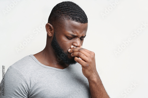 Afro man touching his nose, having runny nose