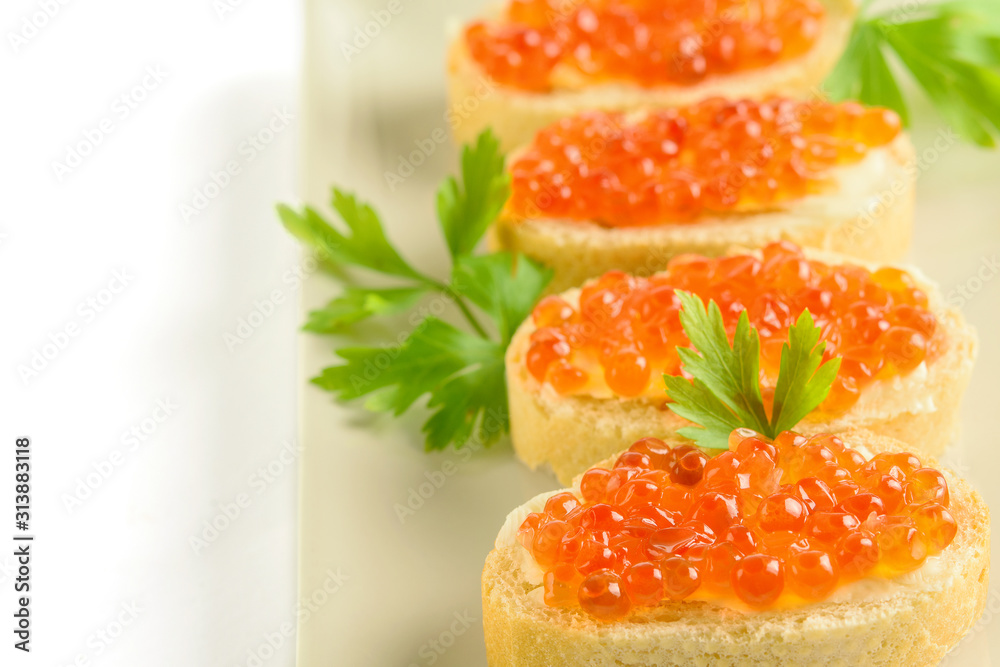Slices of white bread with red fresh caviar and parsley on the white background closeup. Slices of white bread with red fresh caviar and parsley on the white background closeup.