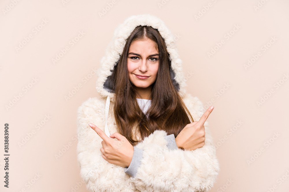 Naklejka premium Young caucasian woman posing isolated points sideways, is trying to choose between two options.