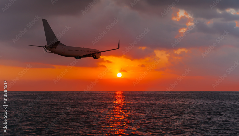 Passenger plane flying over the sea orange sunset