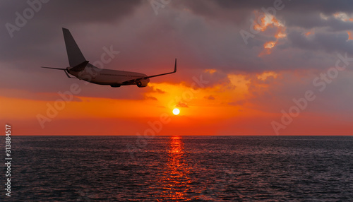 Passenger plane flying over the sea orange sunset