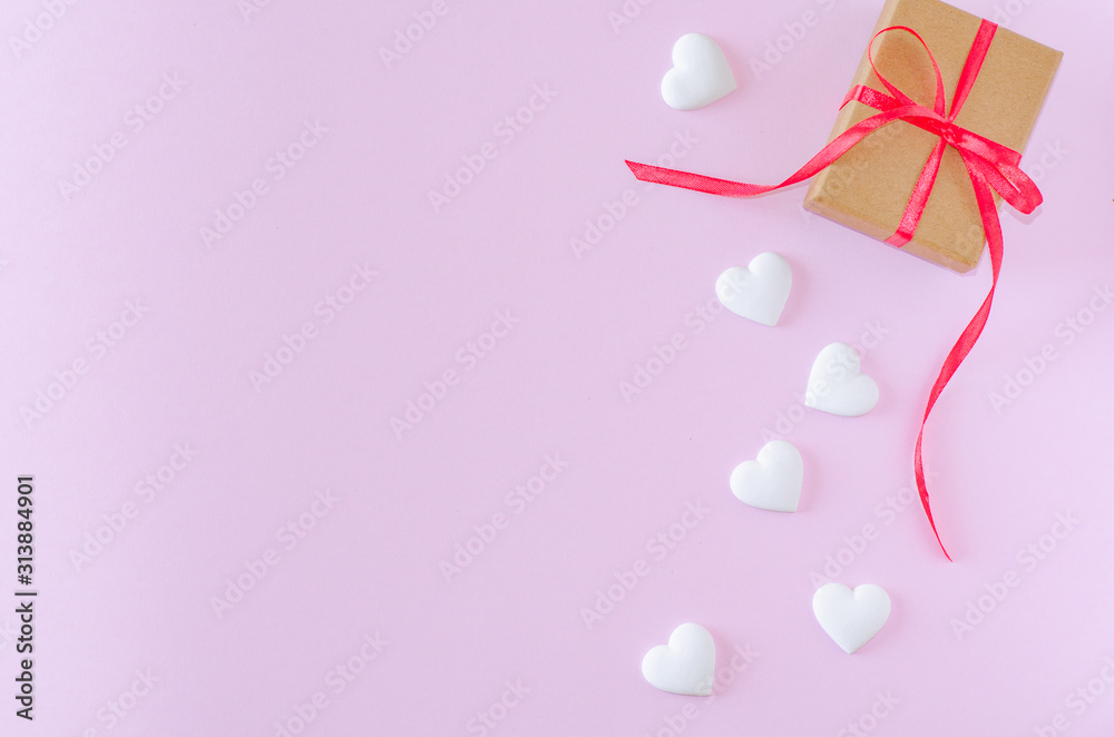 Gift box and white heart on a pink background. Valentine's day and romantic concept. Flat lay. Copy space.