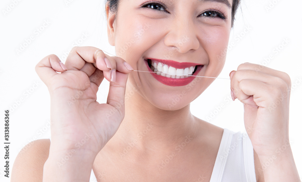 Close up images of Asian young pretty woman, smiling, beautiful white and clean teeth, are using dental floss Clean teeth after eating For good dental health On white background to health care concept Close up images of Asian young pretty woman, smiling, beautiful white and clean teeth, are using dental floss Clean teeth after eating For good dental health On white background to health care concept