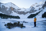 Girl standing looking at a high mountain landscape with an icy lake.