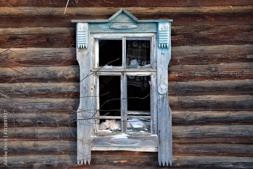 Window with platbands in an old wooden house, glass is smashed.