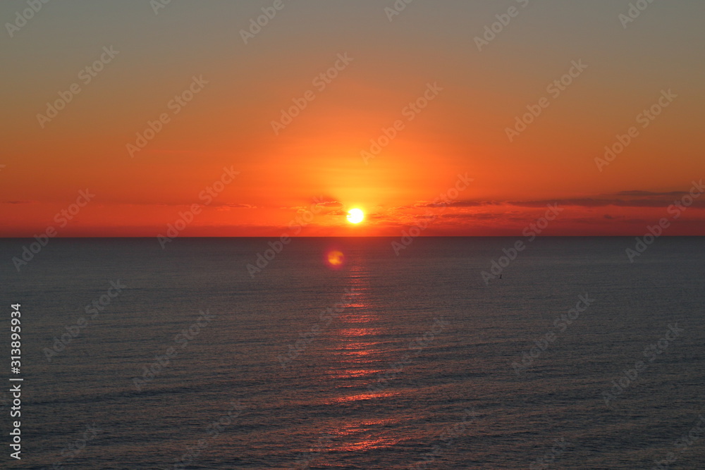 Primeros momentos del amanecer sobre un mar en calma y con el reflejo del sol sobre el agua