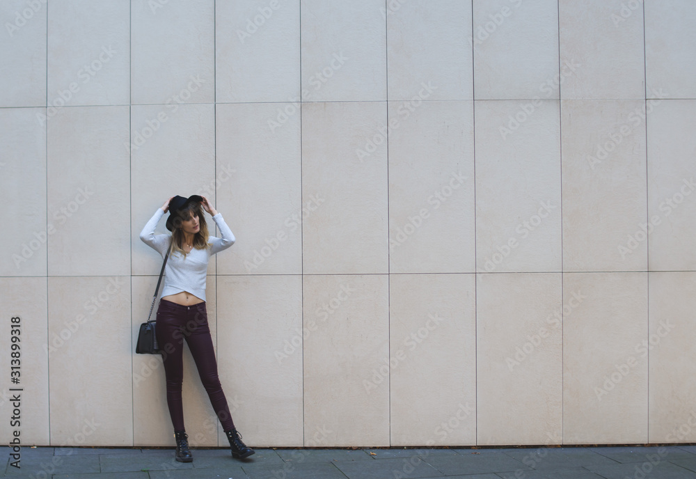 Fototapeta premium Young girl with a black hat posing at a checkered wall