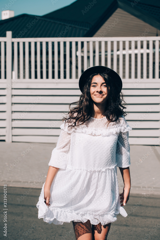 lifestyle portrait of young stylish hipster woman, wearing trendy white dress