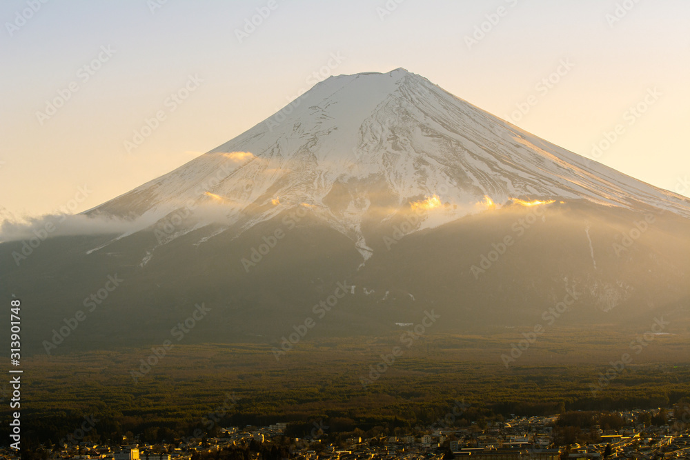 The sun shines on the top of Mount Fuji covered with snow.