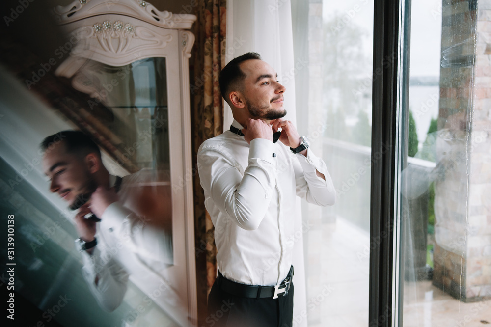 Serious man buttoning his shirt in optimistic mood, getting ready for work Serious man buttoning his shirt in optimistic mood, getting ready for work