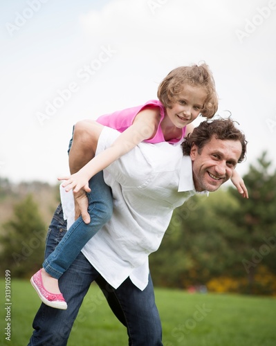 Father giving young daughter piggyback ride