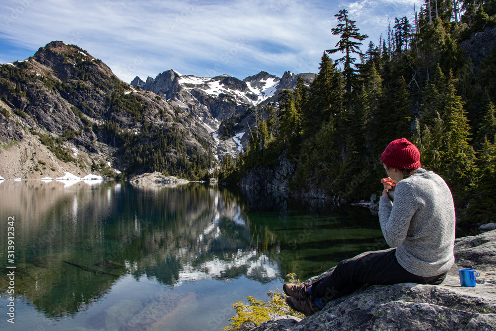 Hipster hiker girl eats breakfast by wild mountain lake in Washington Hipster hiker girl eats breakfast by wild mountain lake in Washington