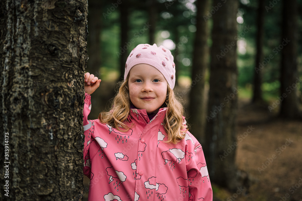 Blonde haired child in forest leaning on tree Blonde haired child in forest leaning on tree
