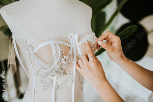 close up of hands sewing a wedding dress photo