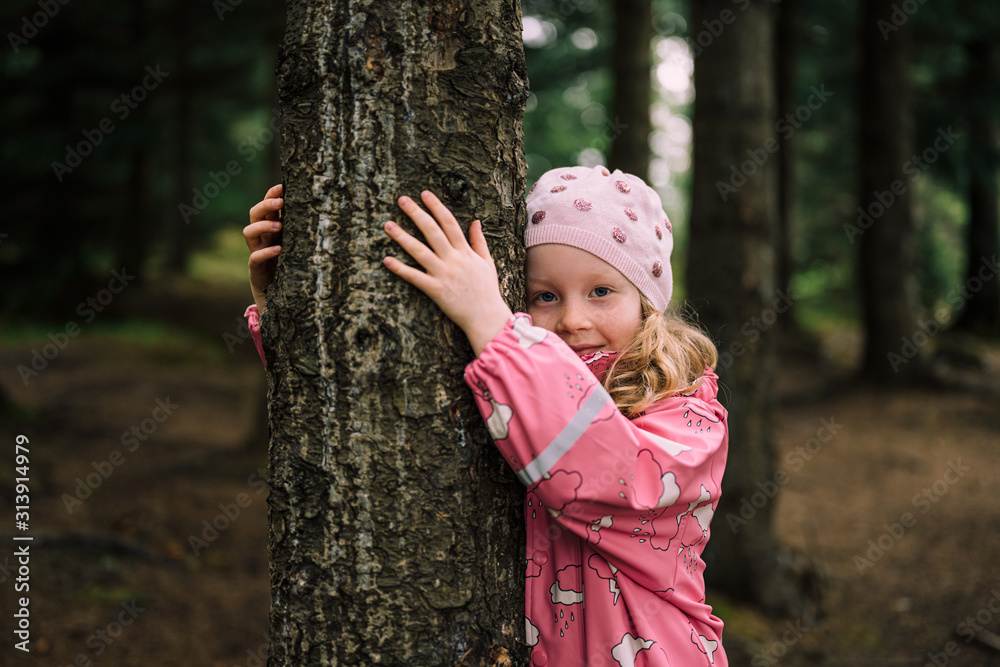Little blonde child in forest hugging tree Little blonde child in forest hugging tree