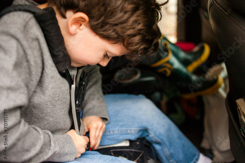 a small child diligently works to buckle himself into own carseat photo