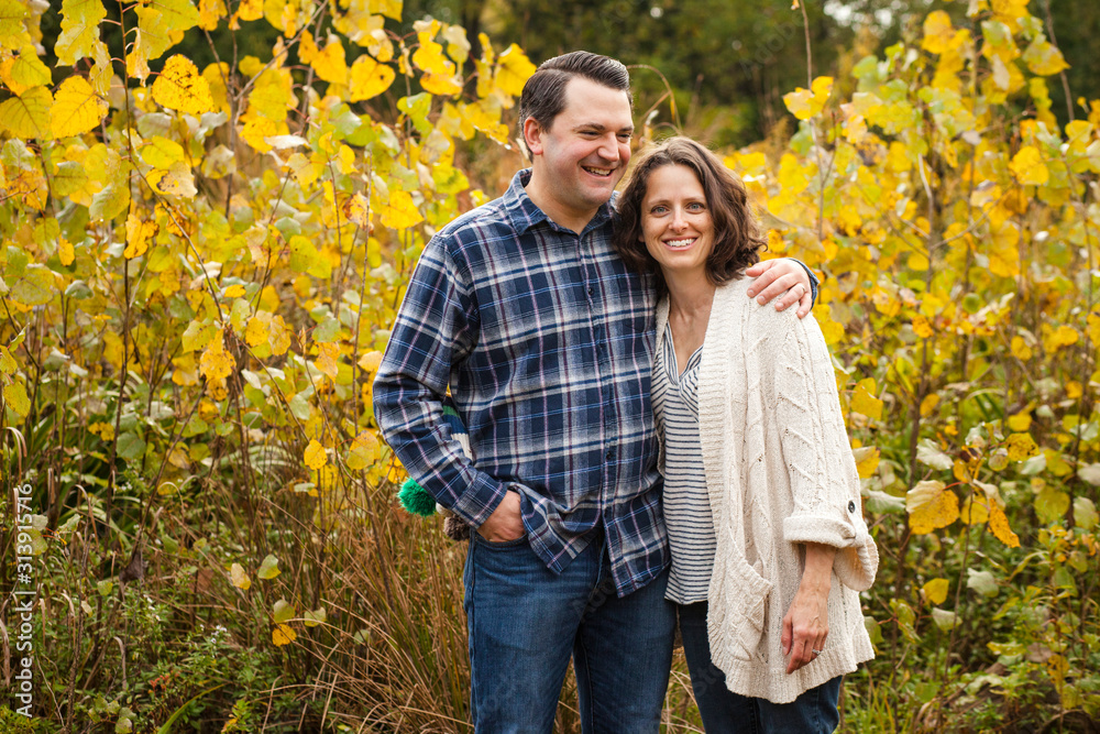 a smiling happy couple stand arm-in-arm in a golden prairie a smiling happy couple stand arm-in-arm in a golden prairie